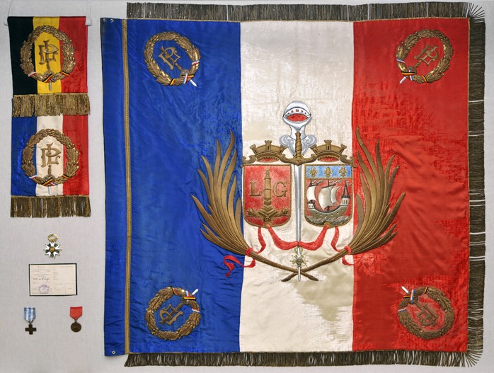 Vitrine installée sur la mezzanine à l’Hôtel de Ville : drapeau de la Ville de Paris offert à la Ville de Liège (avec les blasons des deux cités) à l'occasion de la remise de la Légion d'honneur le 24 juillet 1919, restauré en 2014 par l'IRPA grâce aux subventions de la fondation David-Constant. © Ville de Liège (Tourisme) - M VERPOORTEN